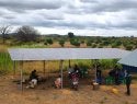 People sitting under solar panel.
