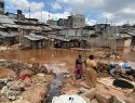 Two people stand on a muddy area near waterlogged homes in Mathare, an informal settlement in Nairobi..