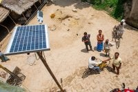 People looking up at a solar panel providing energy for a streetlight.