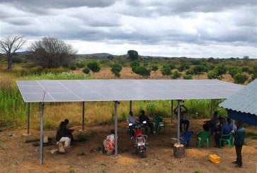 People sitting under solar panel.