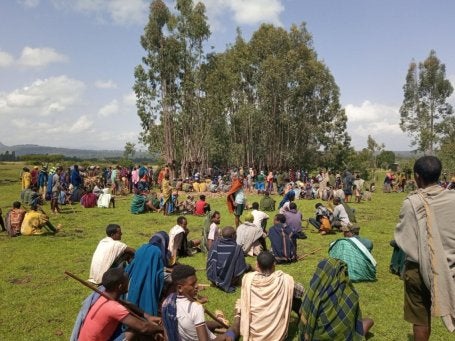 People sitting in a group in a grassy field. 