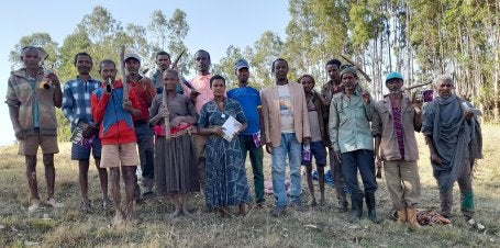 A group of people with farming tools. 