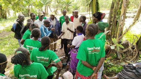 A group of people gathered outdoor in a lush, green setting.