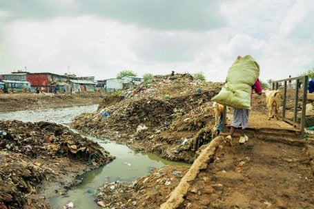 A person carries a large bundle while walking along a path in Mathare.