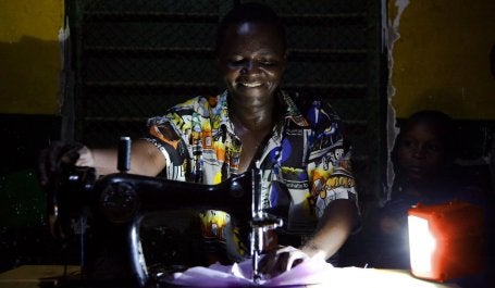 Electricity has far-reaching impacts on people's livelihoods. This Tanzanian tailor can sew at night thanks to solar power. Photo by Theo Steemers/USAID