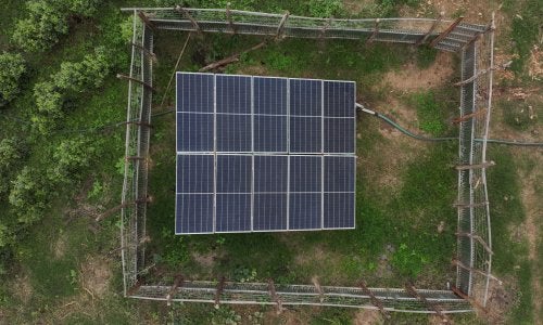 Aerial view of a solar panel array in a farm field.
